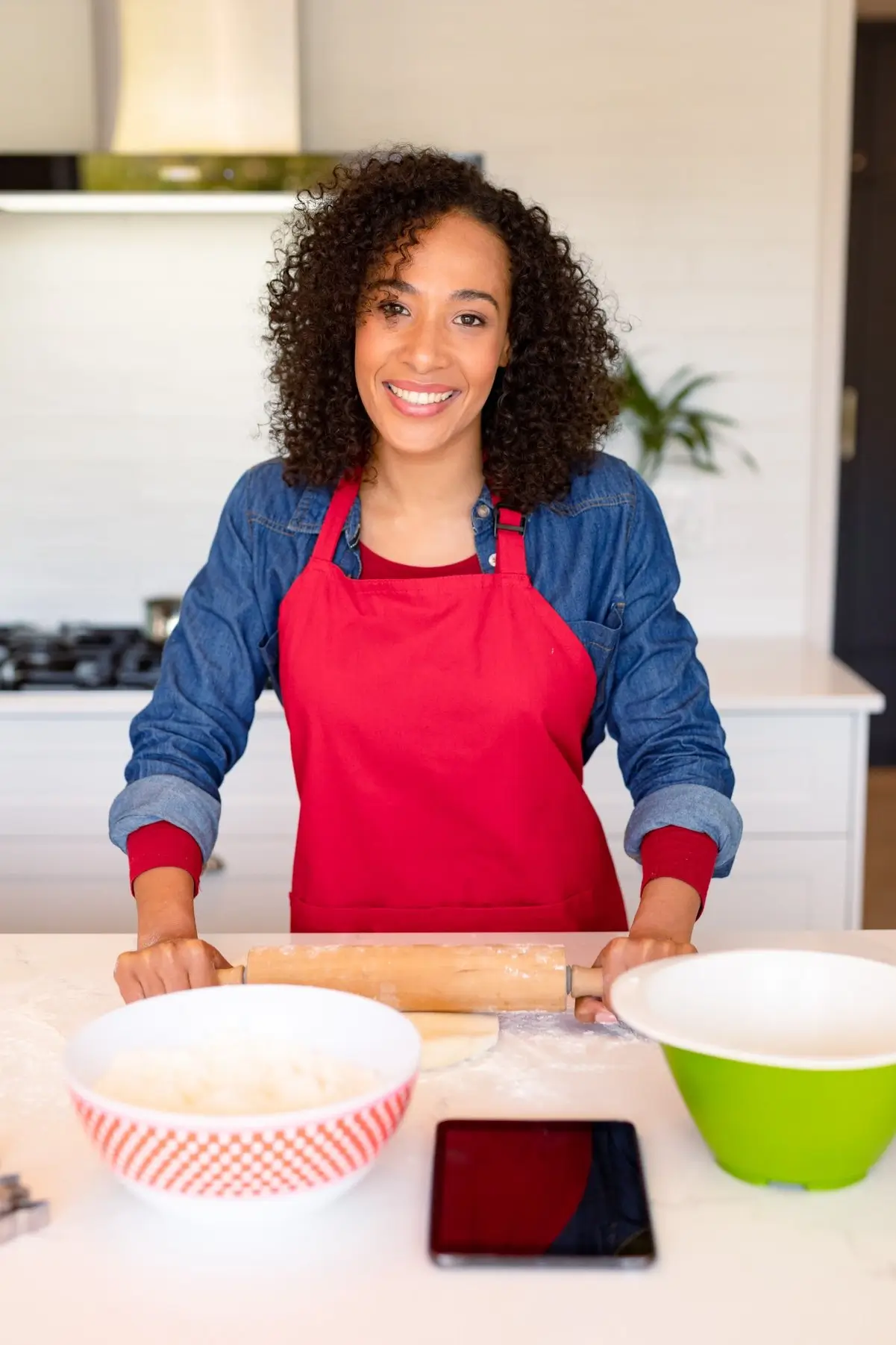Geneviève Lemoine in the kitchen at DoughDazzle, smiling behind a counter with baking tools and mixing bowls.