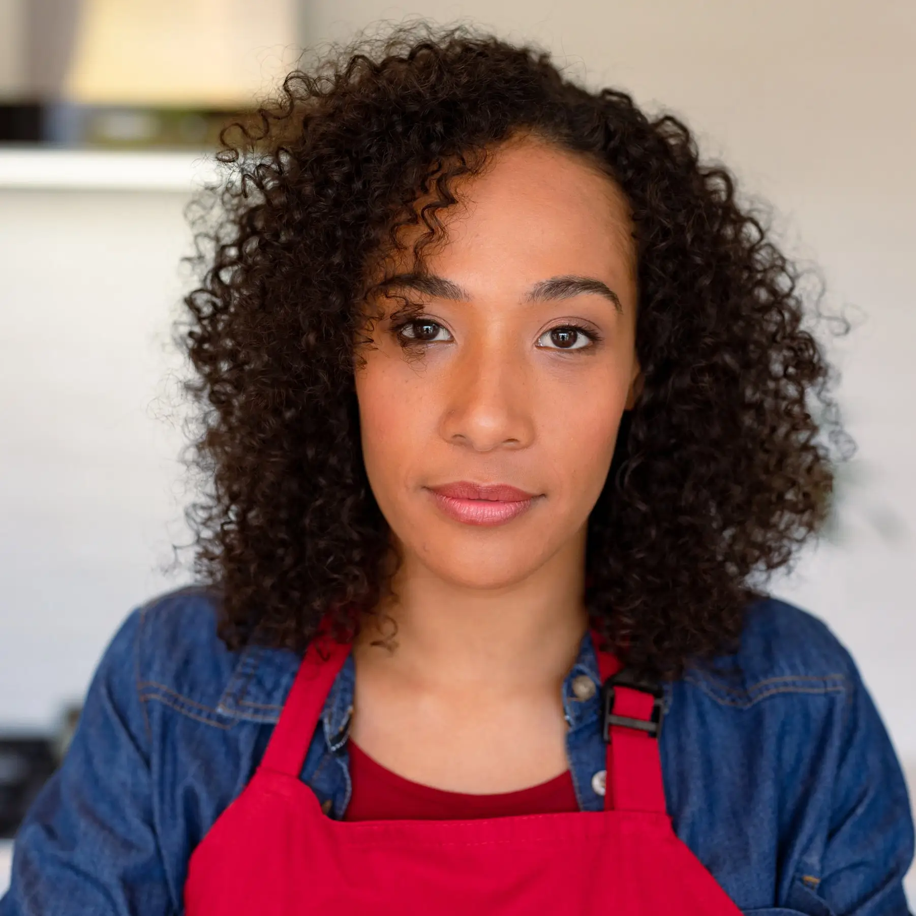 Portrait of Geneviève Lemoine, founder of DoughDazzle, in a bright indoor setting wearing a red apron.