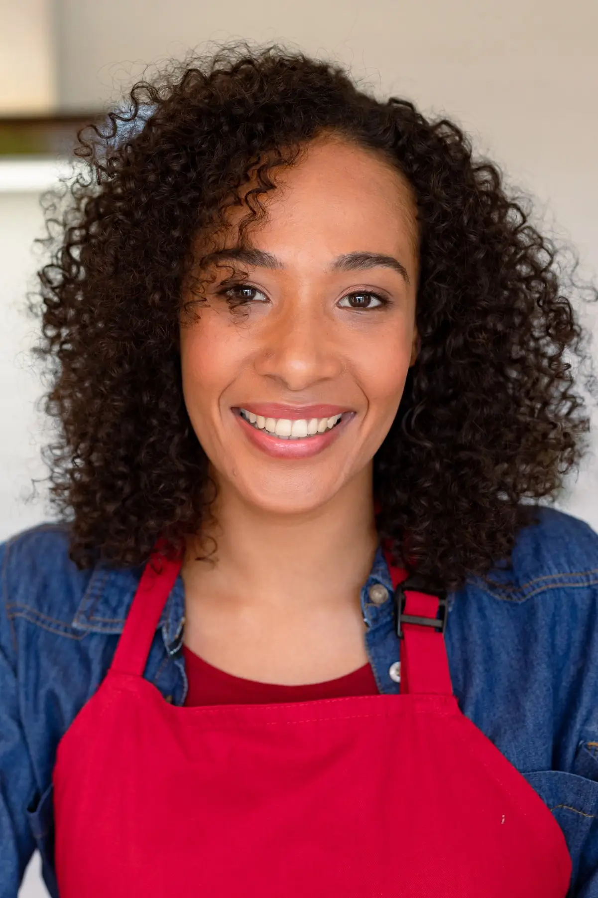 Portrait of Geneviève Lemoine, founder of DoughDazzle, smiling in a bright indoor setting while wearing a red apron.