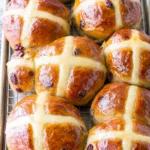 traditional hot cross buns with white crosses and glossy tops on a cooling rack