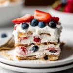 Layered berry icebox cake with whipped cream, strawberries, blueberries, and crackers