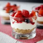 berry yogurt cheesecakes served in mini glass cups with fresh strawberries and blueberries