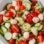 Caprese Salad with Cucumber, cherry tomatoes, and mozzarella in a white bowl