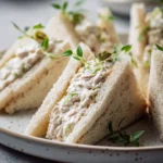 chicken salad tea sandwiches cut into triangles on a serving tray