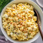 Deviled Egg Macaroni Salad with pasta, eggs, paprika, and herbs in a serving bowl