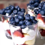 Mini trifles with mixed berries, whipped cream, and cake layered in glass cups