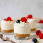 No-Bake Cheesecake Cups topped with whipped cream, raspberries, and blueberries