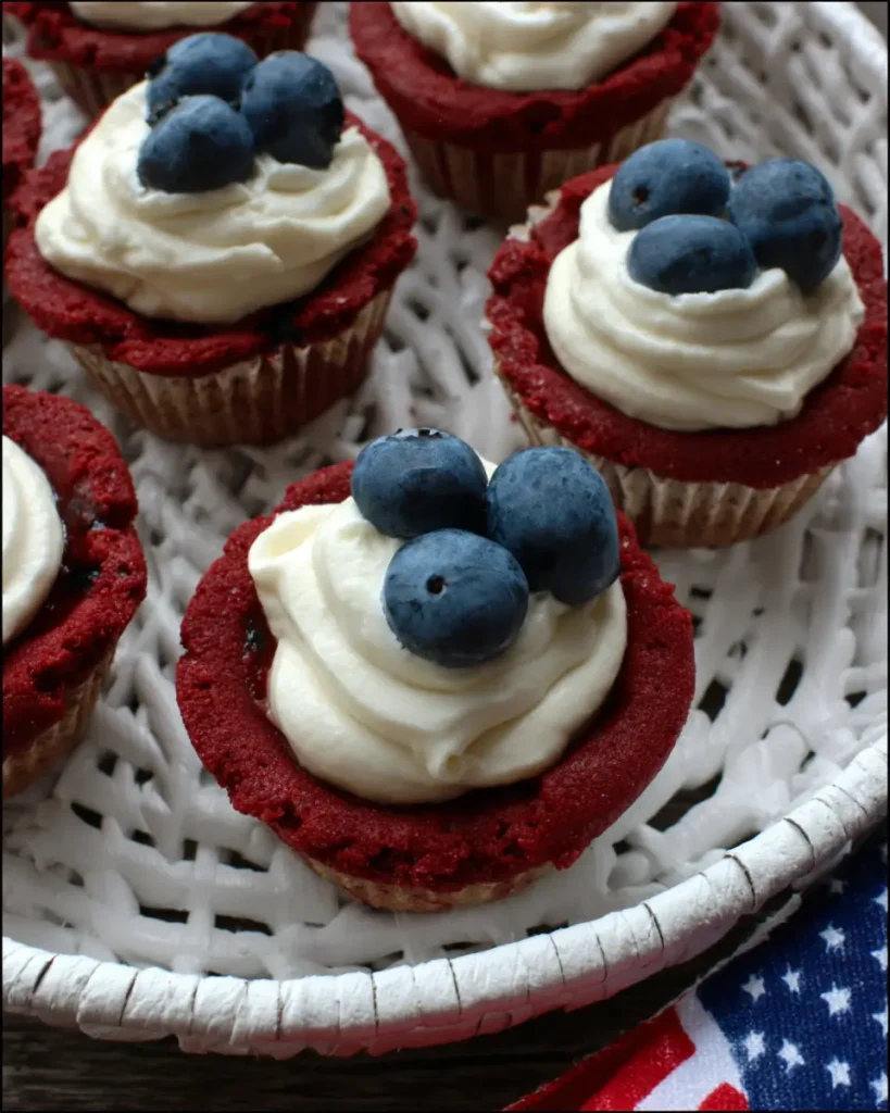 Red white and blue cookie cups topped with cream frosting and fresh blueberries