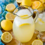 Glass pitcher of fresh summer lemonade Recipe with sliced lemons and ice cubes